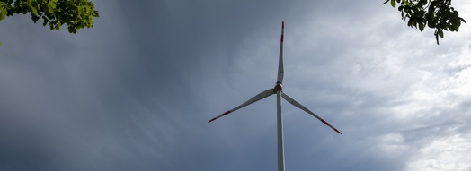 A wind turbine in front of a cloudy sky.